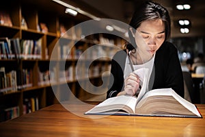 A lovely Asian woman reads a book in the university library to relax and educate herself