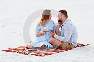 Lovely attractive couple sitting together on the white sand beach, couple with wine or champagne during romantic dinner, young cou