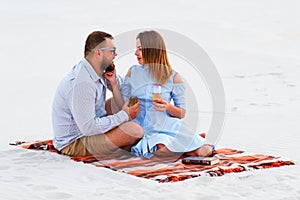 Lovely attractive couple sitting together on the white sand beach, couple with wine or champagne during romantic dinner, young cou