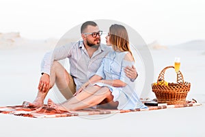 Lovely attractive couple sitting together on the white sand beach, happy couple enjoying picnic on the beach and have good time on