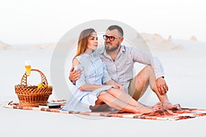 lovely attractive couple sitting together on the white sand beach, happy couple sitting on a blanket , happy couple enjoying