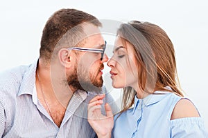 Lovely attractive couple sitting together on the white sand beach, looking each other, young couple kissing on the beach, love, ro