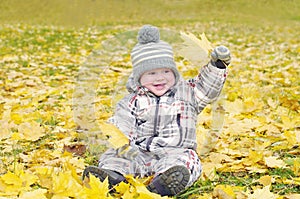 Lovely baby age of 1 year outdoors in autumn plays with leaves