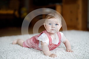 Lovely baby girl in white sunny bedroom. Newborn child learning crawling. Nursery for children. Textile and bedding for