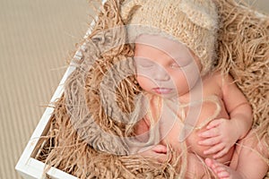 Lovely baby in knitted hat sleeping in wooden box