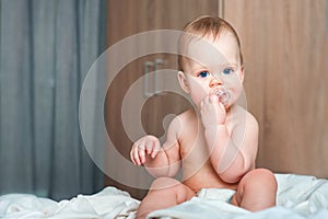 Lovely baby with a pacifier on the bed in the bedroom. Children`s sleep, malocclusion, teething