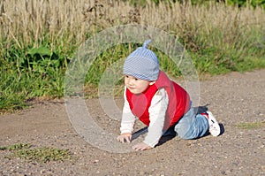 Lovely baby in red waistcoat creeps on ground