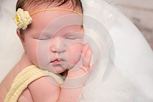 Lovely baby in yellow romper sleeping with legs crossed