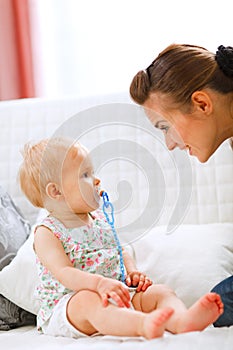 Lovely baby and young mother playing on sofa