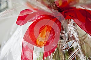 Lovely background with a white design lace wrapping-paper with big red and orange bÐ¾w around the bouquet