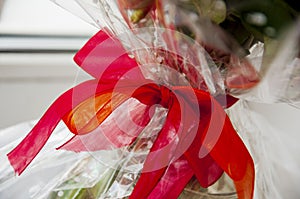 Lovely background with a white design lace wrapping-paper with big red and orange bÐ¾w around the bouquet