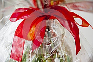 Lovely background with a white design lace wrapping-paper with big red and orange bÐ¾w around the bouquet