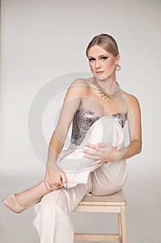 Lovely, beauteous, trendy blond woman with makeup in silver sparkling corset and golden necklace, earrings accessories