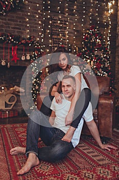 Lovely beautiful couple woman and man are sitting at home near fireplace. Christmas time.