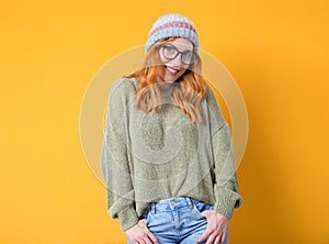 Lovely beautiful young woman smiling while standing with hands in pockets, isolated on yellow background. Half length of pretty