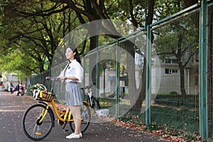 Lovely beauty Asia Chinese high school girl student smile enjoy free time on playground ride bike