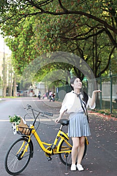 Lovely beauty Asia Chinese high school girl student smile enjoy free time on playground ride bike