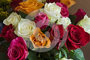 Lovely big colorful bouquet with many flowers  roses of red, vinous, orange and white colors. Green leaves and thorns. Still life.