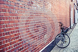 A lovely black bicycle stand alone near red brick wall outdoors