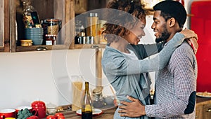 Lovely black couple embracing in cozy kitchen