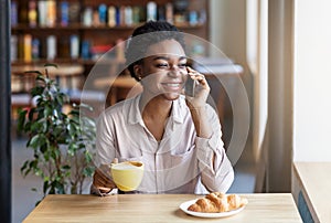 Lovely black girl talking on mobile phone during her lunch at coffee shop