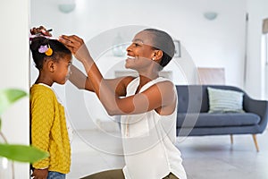 Lovely black mother measuring daughter height against wall at home