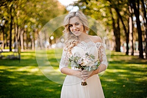 Lovely blonde bride dressed in a beautiful dress standing on the lawn