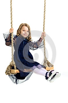 Lovely blonde little girl swinging on rope swing