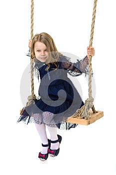 Lovely blonde little girl swinging on rope swing