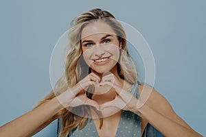 Lovely blonde woman admitting in her love with use of heart gesture photo
