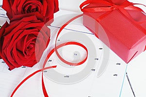 Lovely blooming red color rose flower and elegant gift box on 14 Fab calender background decorated with red ribbon, sweet