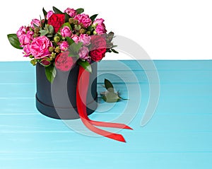 Lovely bouquet of pink and red roses and red ribbon in a circular black box