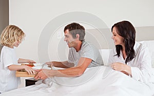 Lovely boy bringing breakfast to his parents