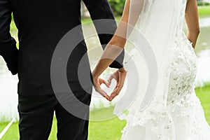 Lovely bride and groom hold hand in heart shape, couples wedding with love forever