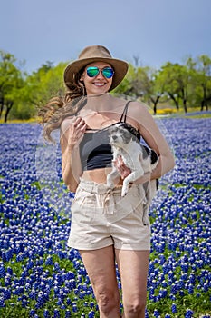A Lovely Brunette Model Poses In A Field Of Bluebonnet Flowers With Her Dog In A Texas Prarie