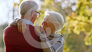 Lovely caucasian heterosexual senior couple. Outdoor portrait of two senior pensioners hugging in the park, enjoying