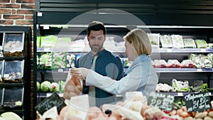 Lovely caucasian marriage couple shopping in grocery store in produce section