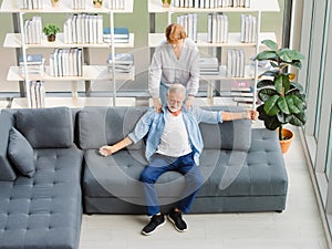 Lovely caucasian senior elderly wife standing massage happy white hair and bearded husband shoulder sitting relaxing resting on