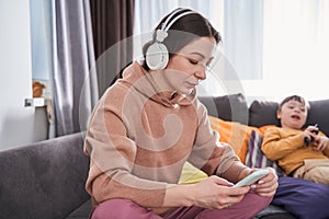 Lovely caucasian woman looking at the smartphone screen while sitting at the sofa