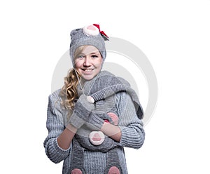 Lovely cheerful teenage girl wearing fuzzy sweater, scarf, mittens and hat isolated on white background. Winter clothes.