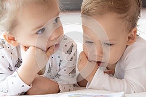 Lovely children - brother and sister, reading a book, on the bed. Close up of children in bed reading a book. A boy and
