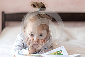 Lovely children - brother and sister, reading a book, on the bed. Close up of children in bed reading a book. A boy and