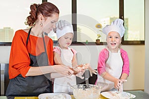 Lovely children together with mother preparing a cake