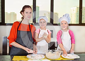 Lovely children together with mother preparing a cake