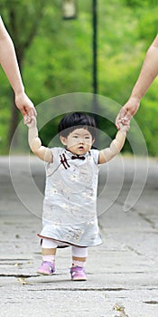 Lovely Chinese baby girl in cheongsam learn to walk