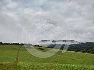 Krásné mraky nad městem a domy nebo parkem a loukou, při východu nebo západu slunce.