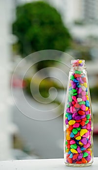 Lovely colorful small pebbles with pink, blue, green, grey and white pebbles in a clear glass bottle