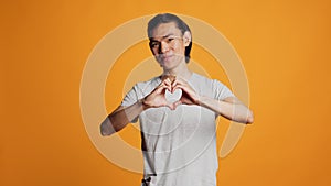 Lovely confident guy doing heart shape sign on camera