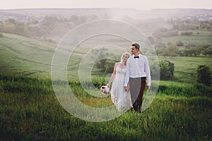 Lovely couple, bride and groom posing in field during sunset, lifestyle