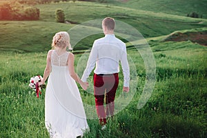 Lovely couple, bride and groom posing in field during sunset, lifestyle